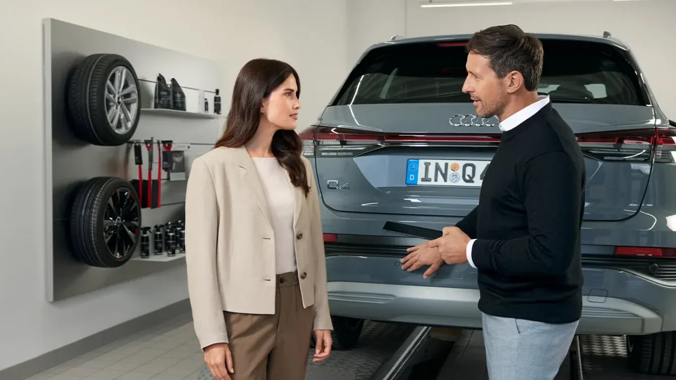Asesor de posventa conversa con una clienta junto a un Audi